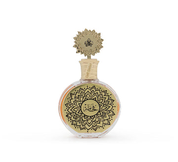 A round glass perfume bottle with a gold-toned lid and a gold label featuring black mandala-style patterns and Arabic calligraphy, set against a plain white background.
