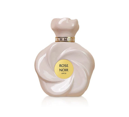 A perfume bottle shaped like a glossy pale pink rose, with a gold circular label reading ROSE NOIR APPLI and a gold neck band, centered on a white background.